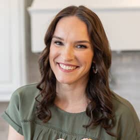 Lindsay, author of Life Love and Sugar, holding a plate of cupcakes and smiling.